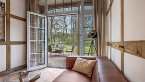 A room with a leather sofa, a glass coffee table, and a telescope.