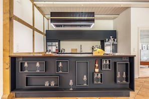 Una cocina moderna con encimera oscura, copas de vino y una botella.