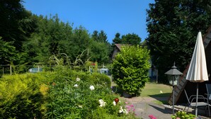 A garden with various plants and flowers, a small tree, and outdoor furniture. - Holiday Home 'Haus Paradiesecke' with Private Terrace, Garden and Wi-Fi (Waldbrunn)
