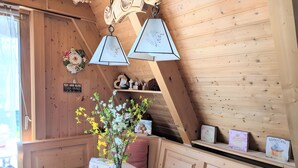 A wooden interior with a bed, a vase with flowers, and a shelf with items. - Holiday Home 'Haus Paradiesecke' with Private Terrace, Garden and Wi-Fi (Waldbrunn)