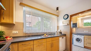Una cucina moderna con mobili in legno, lavastoviglie, forno a microonde e una finestra con tende leggere.