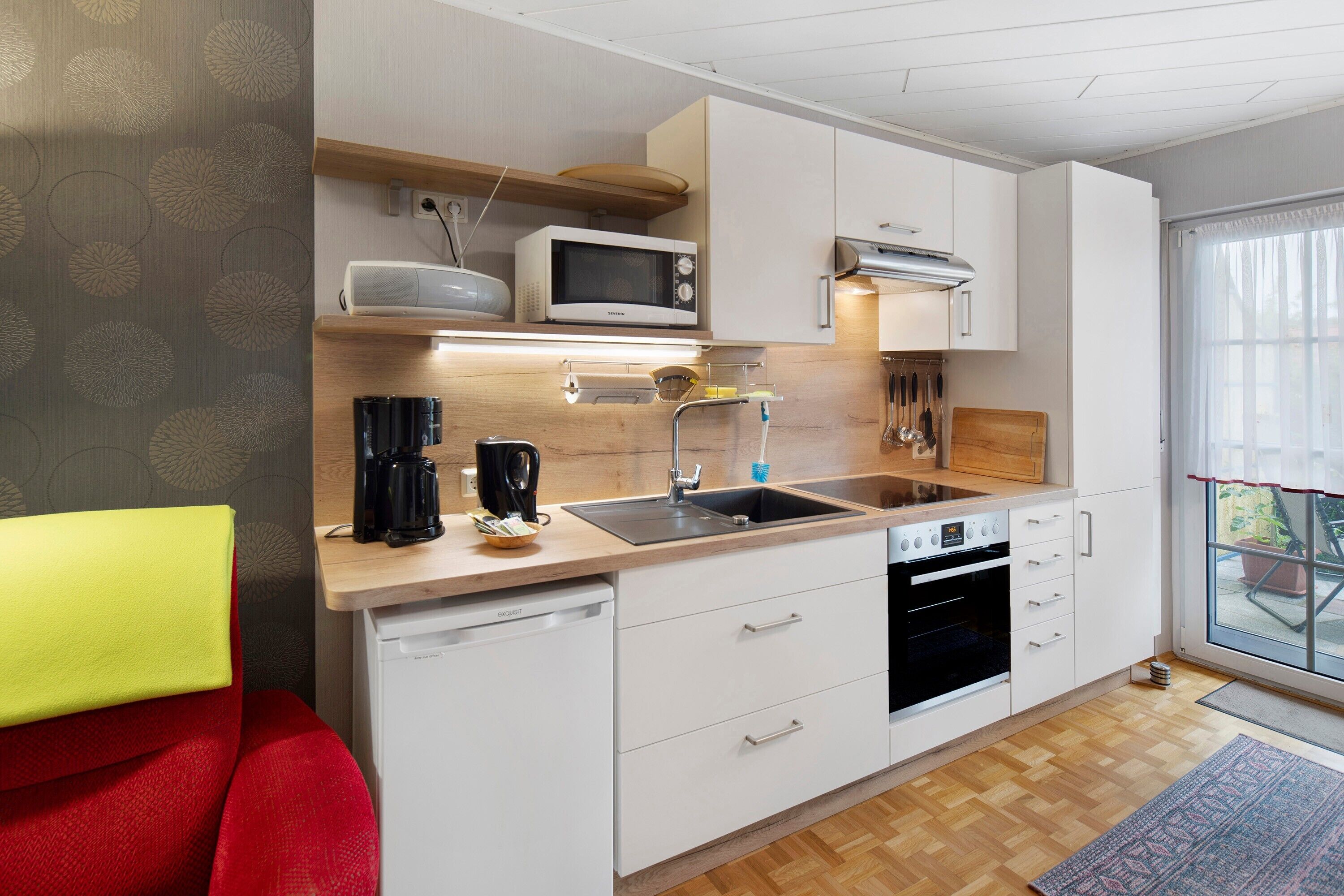 Een moderne keuken met een magnetron, spoelbak en oven.