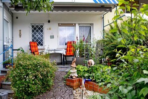 A house with a garden, a gnome statue, and a chair with a red and yellow blanket.
