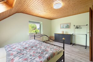 Une chambre à coucher avec un lit, une fenêtre, une commode et un radiateur.