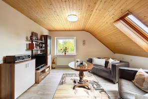 Un salon chaleureux avec un plafond en bois, une télévision, un canapé et une table à manger.