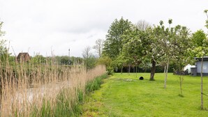 A grassy area with a pond, trees, and a building in the background.