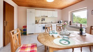 A kitchen with wooden cabinets, a dining table with chairs, and a window with a view.
