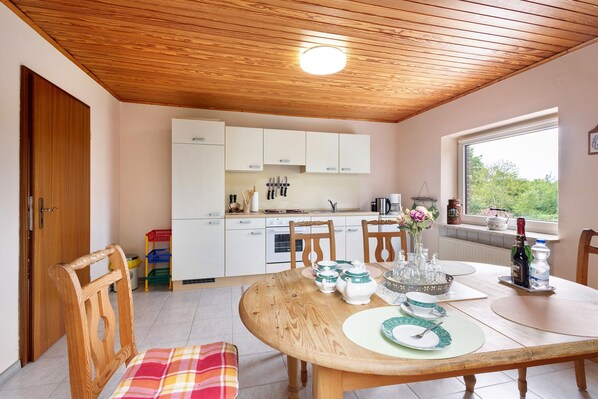 Une cuisine avec des meubles en bois, une table à manger avec des chaises et une fenêtre donnant sur un beau paysage.