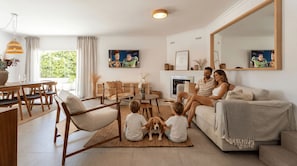 Een woonkamer met een bank, stoelen, een eettafel en een open haard.