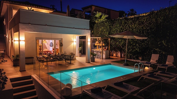 Ein modernes Haus mit Schwimmbad, Sitzgelegenheiten im Freien und einer gut beleuchteten Terrasse.