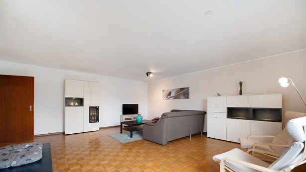 Een moderne woonkamer met een bank, een fauteuil, een televisie en een kast.