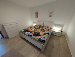 Makuuhuoneessa on sänky, yöpöydät, lipasto ja kaksi seinälle ripustettua taulua.