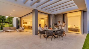 An outdoor dining area with a modern patio, a built-in grill, and a cozy seating arrangement.