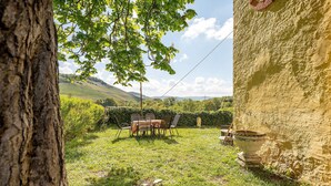 A rustic outdoor dining area with a table and chairs, surrounded by greenery and a view of hills. - Apartment 'Wohnen Auf Dem Weingut - Klein Und Fein' with Shared Terrace, Shared Garden and Wi-Fi (Maring-Noviand)