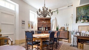 A dining room with a wooden table, chairs, a chandelier, and a patterned rug. - Apartment 'Napoleonzimmer Studio' with Shared Terrace, Shared Garden and Wi-Fi (Maring-Noviand)