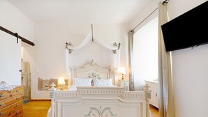 A bedroom with a four-poster bed, a wooden dresser, and a television mounted on the wall. - Apartment 'Napoleonzimmer Studio' with Shared Terrace, Shared Garden and Wi-Fi (Maring-Noviand)