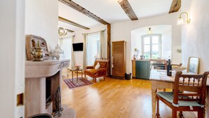 A cozy living room with a fireplace, wooden floors, a dining table, and a kitchen area. - Apartment 'Napoleonzimmer Studio' with Shared Terrace, Shared Garden and Wi-Fi (Maring-Noviand)
