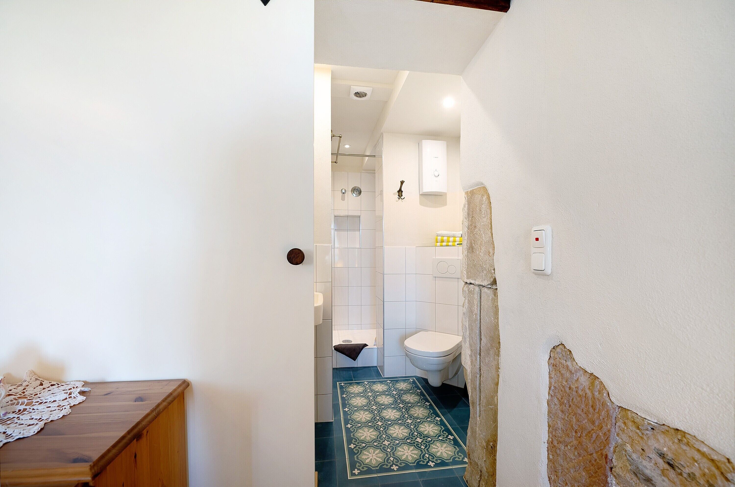 Et badeværelse med toilet, bruser og et gulv med mønster.