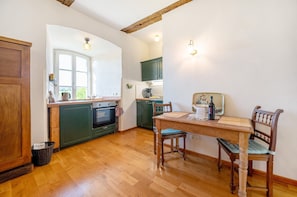 A kitchen with wooden cabinets, a dining table with chairs, and a window.