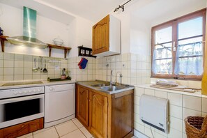 Une cuisine équipée d’une cuisinière, d’un four, d’un évier et de meubles de rangement en bois.