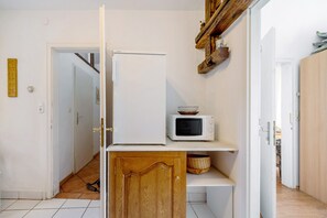 Une cuisine avec un réfrigérateur blanc, un four à micro-ondes et des armoires en bois.