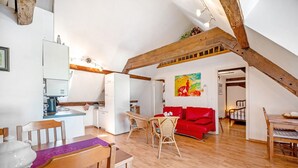 Een interieur met een eethoek, keuken en een rode bank.