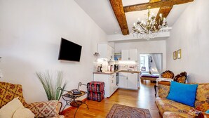 Uma sala de estar com sofá, mesa de centro e televisão na parede.