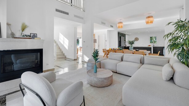 A spacious living area with a fireplace, a large sectional sofa, and a dining area with wooden furniture. - VILLA FALDO VACATION MARBELLA (Nueva Andalucía)