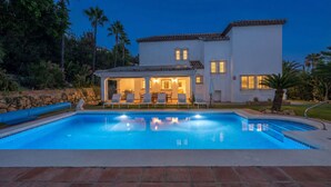 A poolside view of a house with a covered patio, a swimming pool, and a well-maintained garden. - VILLA FALDO VACATION MARBELLA (Nueva Andalucía)