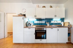 A kitchen with white cabinets, a stainless steel oven, a coffee maker, and a blue tiled backsplash.