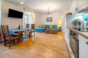 A modern living room with a dining area, a sofa, a TV, and a kitchen with a microwave.