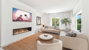 Uma sala de estar moderna com lareira, um sofá, uma mesa de centro e uma TV fixada na parede.