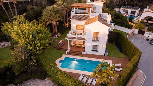 Uma casa com vários andares, piscina, área de estar externa e um jardim bem cuidado.