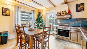A kitchen with wooden cabinets, a built-in oven, and a dining area with a wooden table and chairs. - Apartment 'Ferienhaus Fichtelberg Apartement A' with Mountain View, Private Terrace and Wi-Fi (Oberwiesenthal)