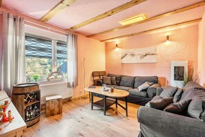 Un salon chaleureux avec un plafond en bois, un canapé, une table basse et une fenêtre avec des rideaux.
