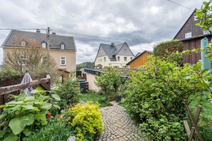 Un quartier résidentiel avec des maisons, un sentier pavé de pierres et une végétation luxuriante.
