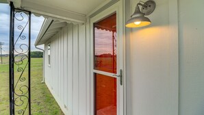 Une façade blanche, une porte en verre et un portail en métal.