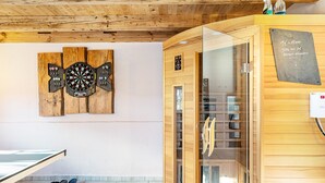 Un interior de madera con mesa de ping pong, sauna y dardo en la pared.