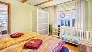 Una habitación con dos camas, un armario blanco, un balcón con vistas y techo de madera.