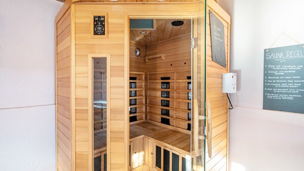 Una sauna con paredes de madera, un panel de control y un cartel con instrucciones.