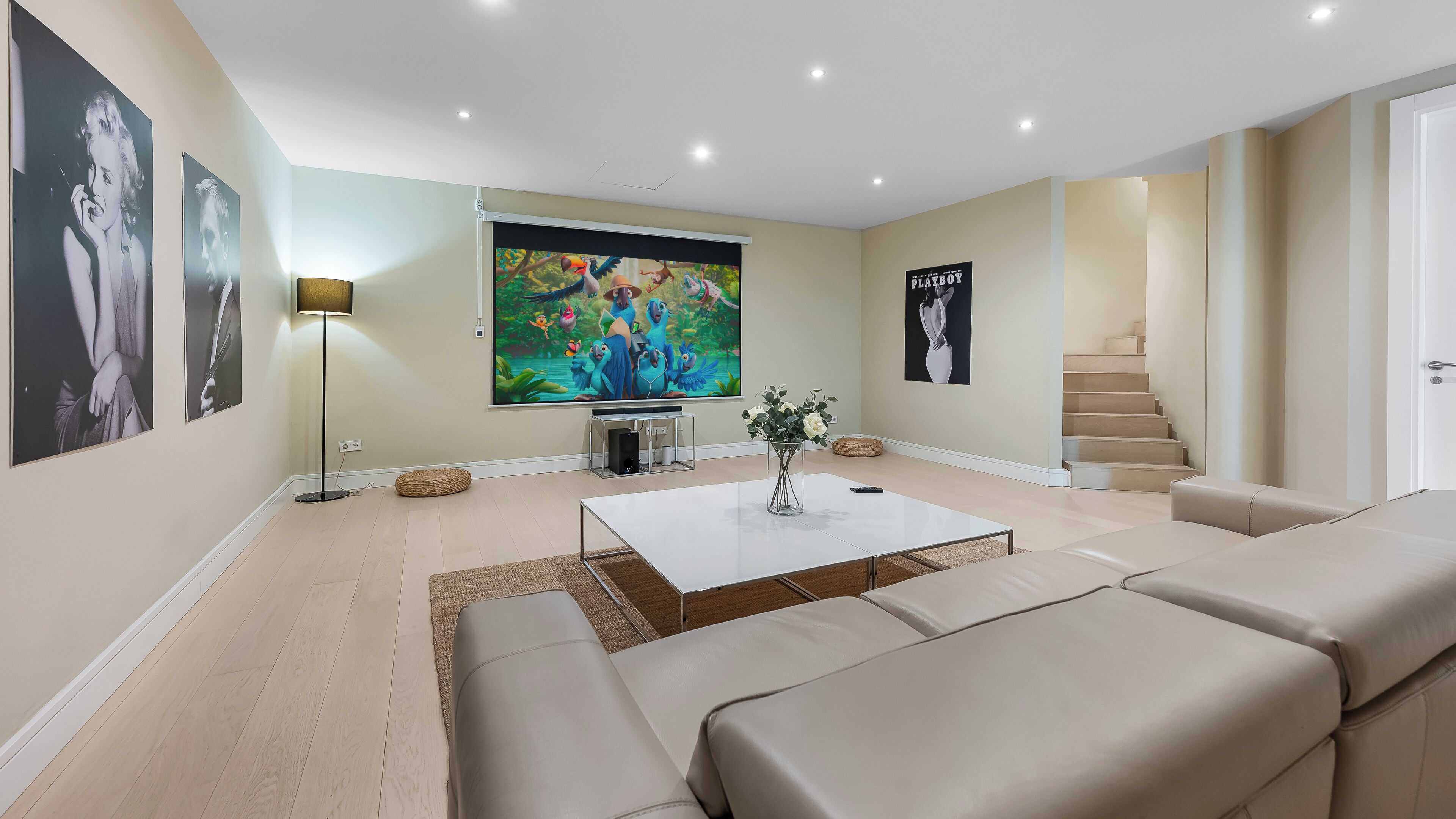 Un salon moderne avec un téléviseur à écran plat, une table basse, des canapés et un escalier.