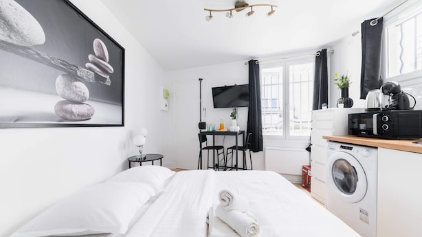 Une chambre d’hôtel équipée d’un lit, d’un bureau, d’une machine à laver et d’une t élévision.