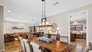 A dining area with a wooden table, leather chairs, and a chandelier. - 4BR: Hot tub, Pool/ Fireplaces/ Grill/ Family Fun (Fredericksburg)