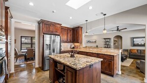 A spacious kitchen with wooden cabinets, a granite countertop, and a built-in island. - 4BR: Hot tub, Pool/ Fireplaces/ Grill/ Family Fun (Fredericksburg)