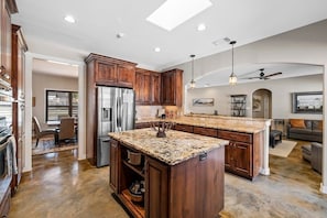 A spacious kitchen with wooden cabinets, a granite countertop, and a built-in island.