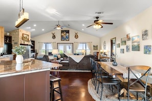 A spacious living area with a large island, a dining table, and a kitchen area with a stone accent wall.