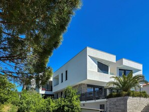 Un edificio moderno de dos plantas con techo plano, ventanas amplias y fachada de piedra.