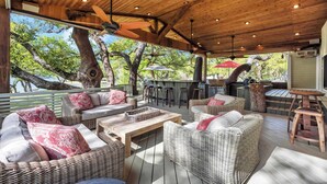 Eine Terrasse im Freien mit Korbmöbeln, einer Holzbalkendecke und einer Bar.