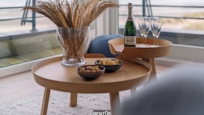 Een tafel met een champagnefles, twee glazen en een vaas met gedroogde planten.