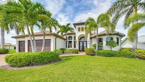 A residential house with a well-maintained lawn, palm trees, and a garage.